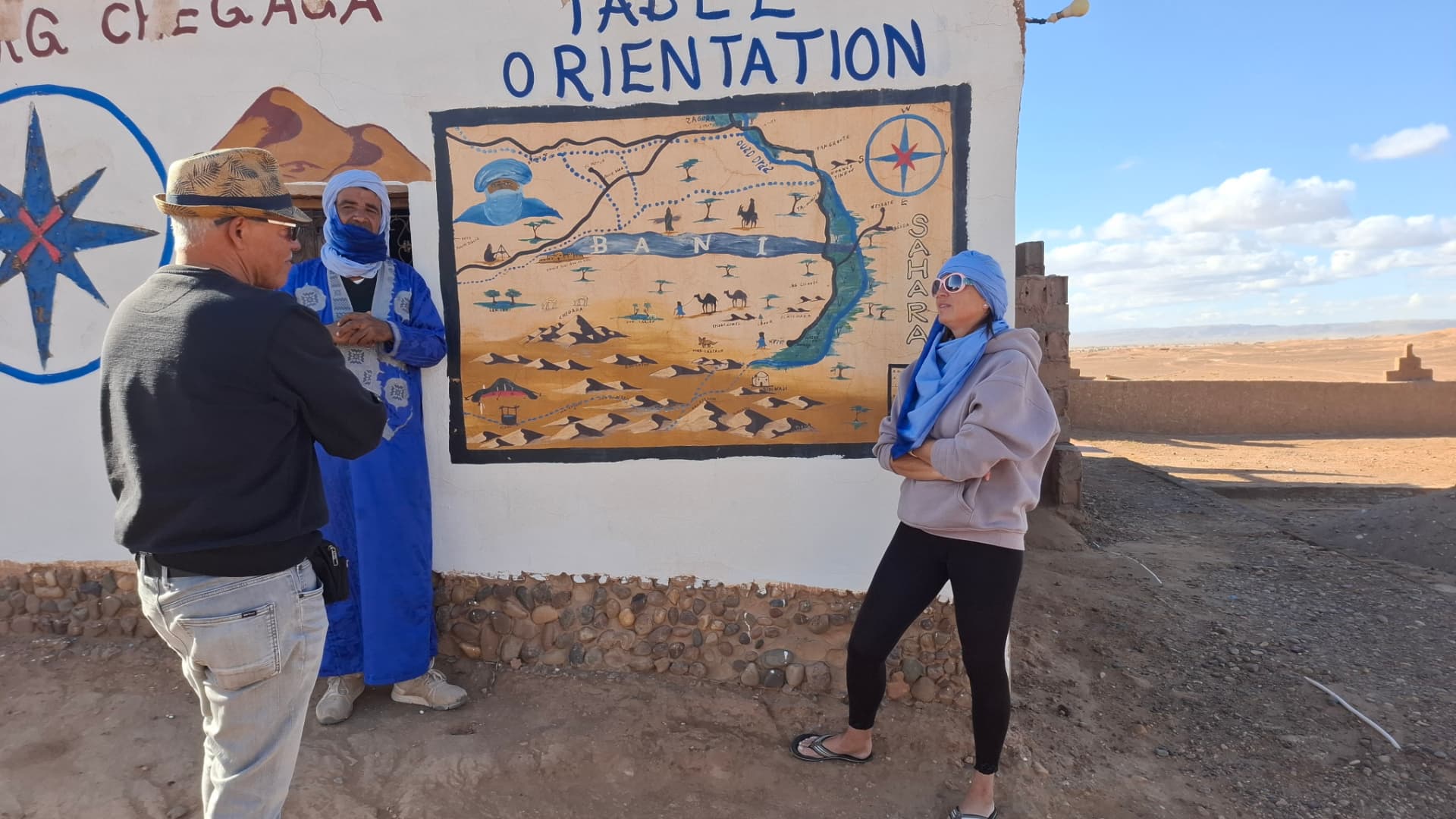 Gespräch vor einer handgemalten Wüstenkarte am Rande der Sahara